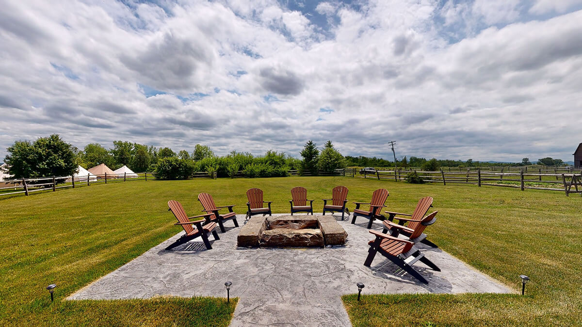 Scenic view of pasture from fire pit with Adirondack chairs at wedding venue.